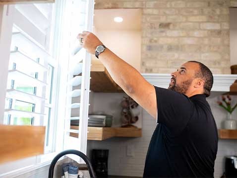 A man inspecting some window shades